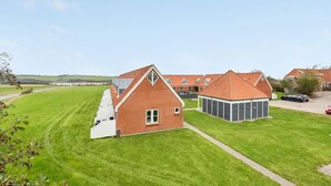 Un quartier résidentiel avec une grande maison en briques, un garage et une pelouse bien entretenue.