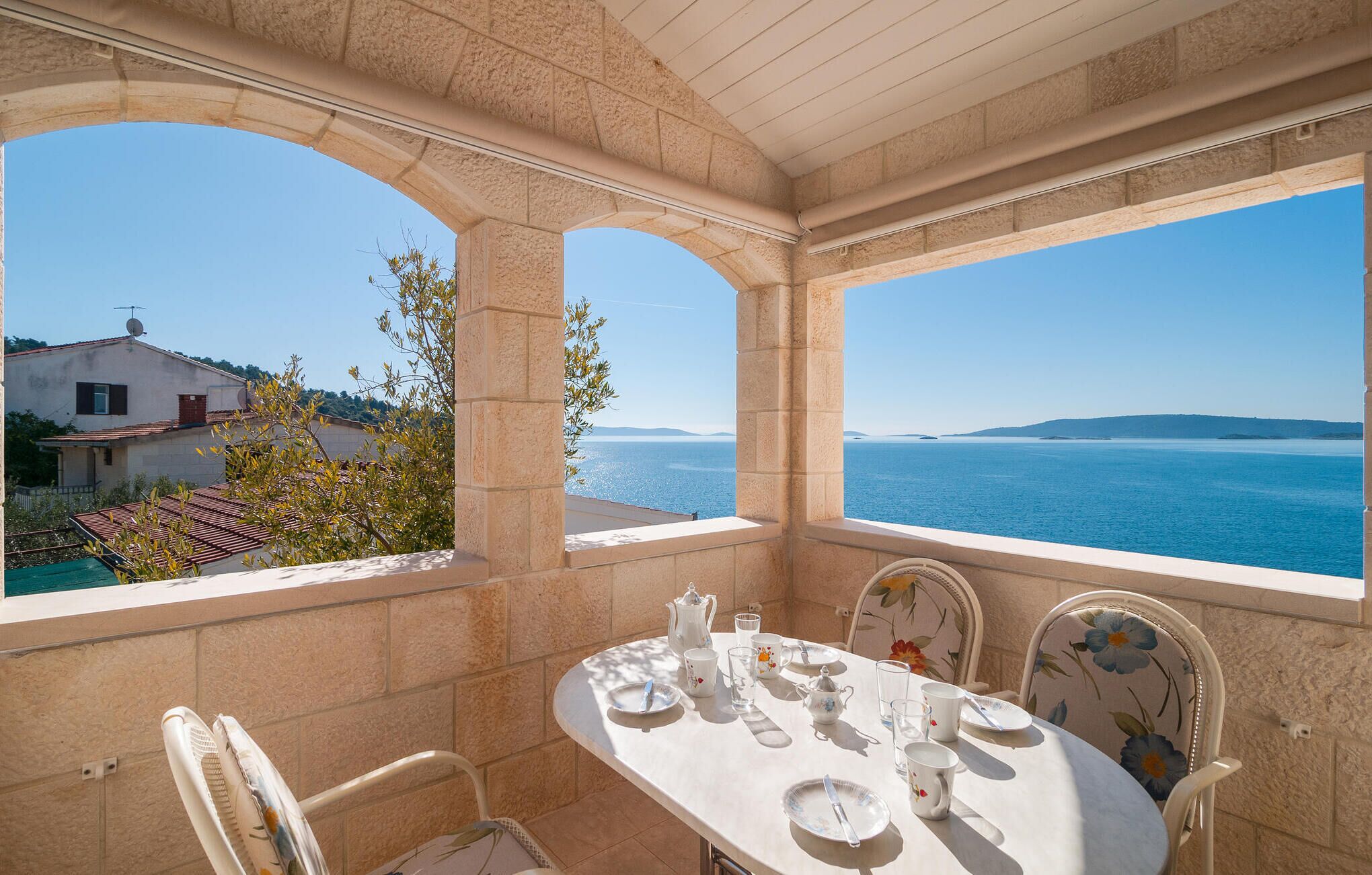 A dining area with a table set for two, overlooking a coastal view.