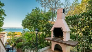 An outdoor kitchen with a stone bench and a view of the sea. - Cozy apartment in Njivice with WiFi (Njivice)