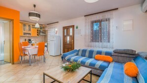 A living room with a sofa, coffee table, and dining area with chairs and a table. - Cozy apartment in Njivice with WiFi (Njivice)