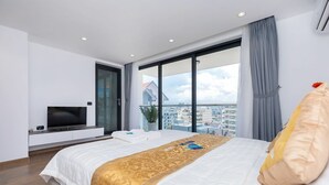 A modern hotel room with a large bed, a flat-screen TV, a balcony with a city view, and a large window. - Tran Duy Luxury Villa 3 (Ho Chi Minh City)