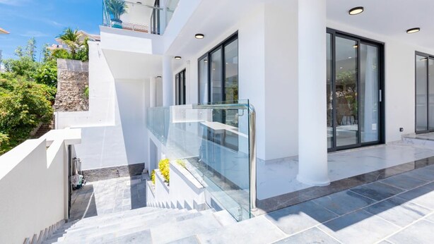 A modern building with a glass balcony, a stone wall, and a staircase leading to a higher level. - Tran Duy Luxury Villa 3 (Ho Chi Minh City)