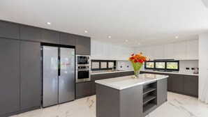 A modern kitchen with grey cabinetry, stainless steel appliances, and a marble floor. - Tran Duy Luxury Villa 3 (Ho Chi Minh City)