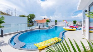 A swimming pool with a curved edge, surrounded by a glass railing, and featuring inflatable toys. - Tran Duy Luxury Villa 3 (Ho Chi Minh City)