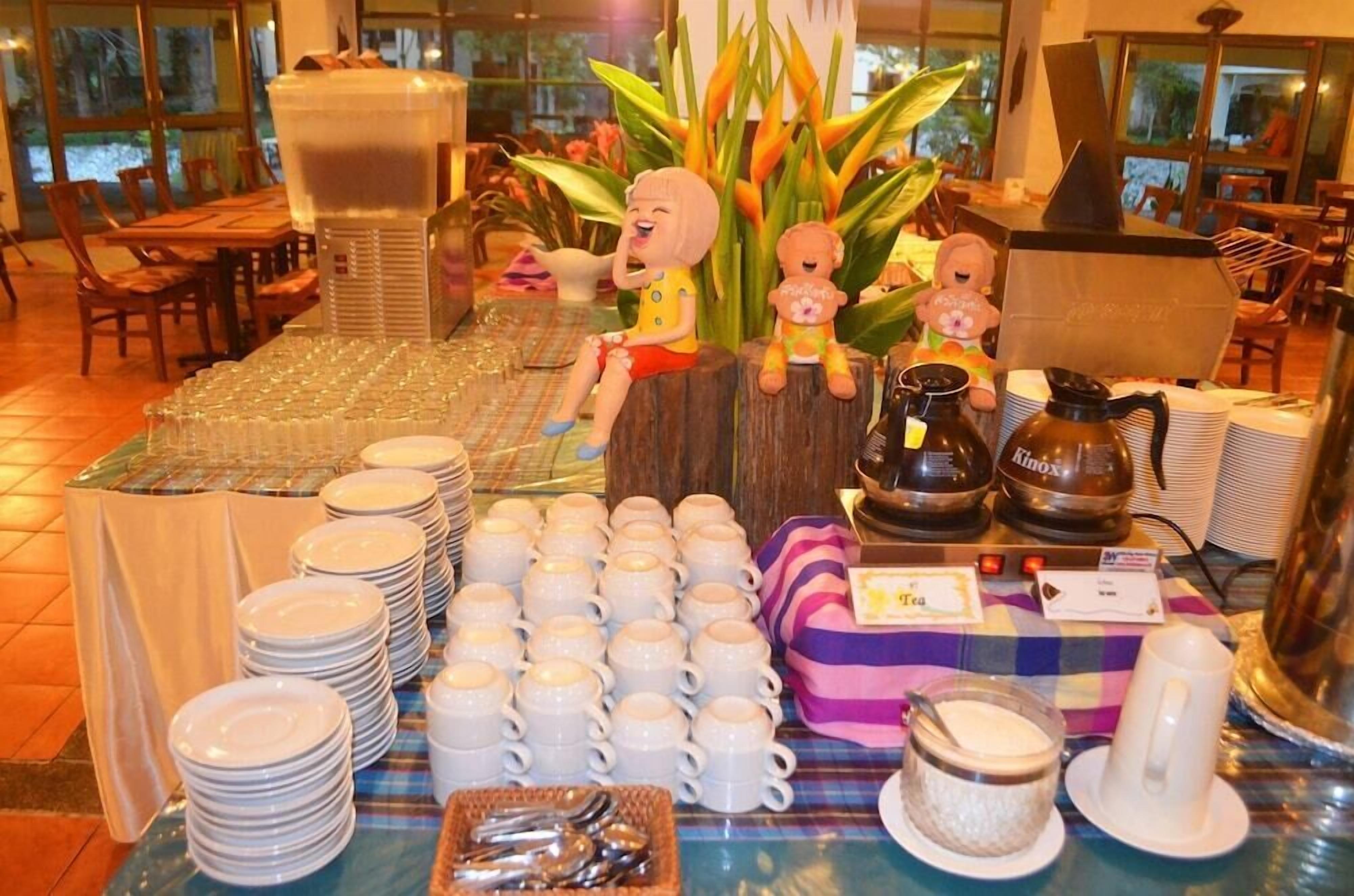 A buffet setup with stacks of plates and cups, a coffee machine, and decorative items.