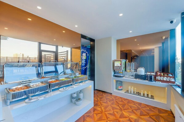 A buffet setup with various food options, a coffee machine, and a seating area with a view.
