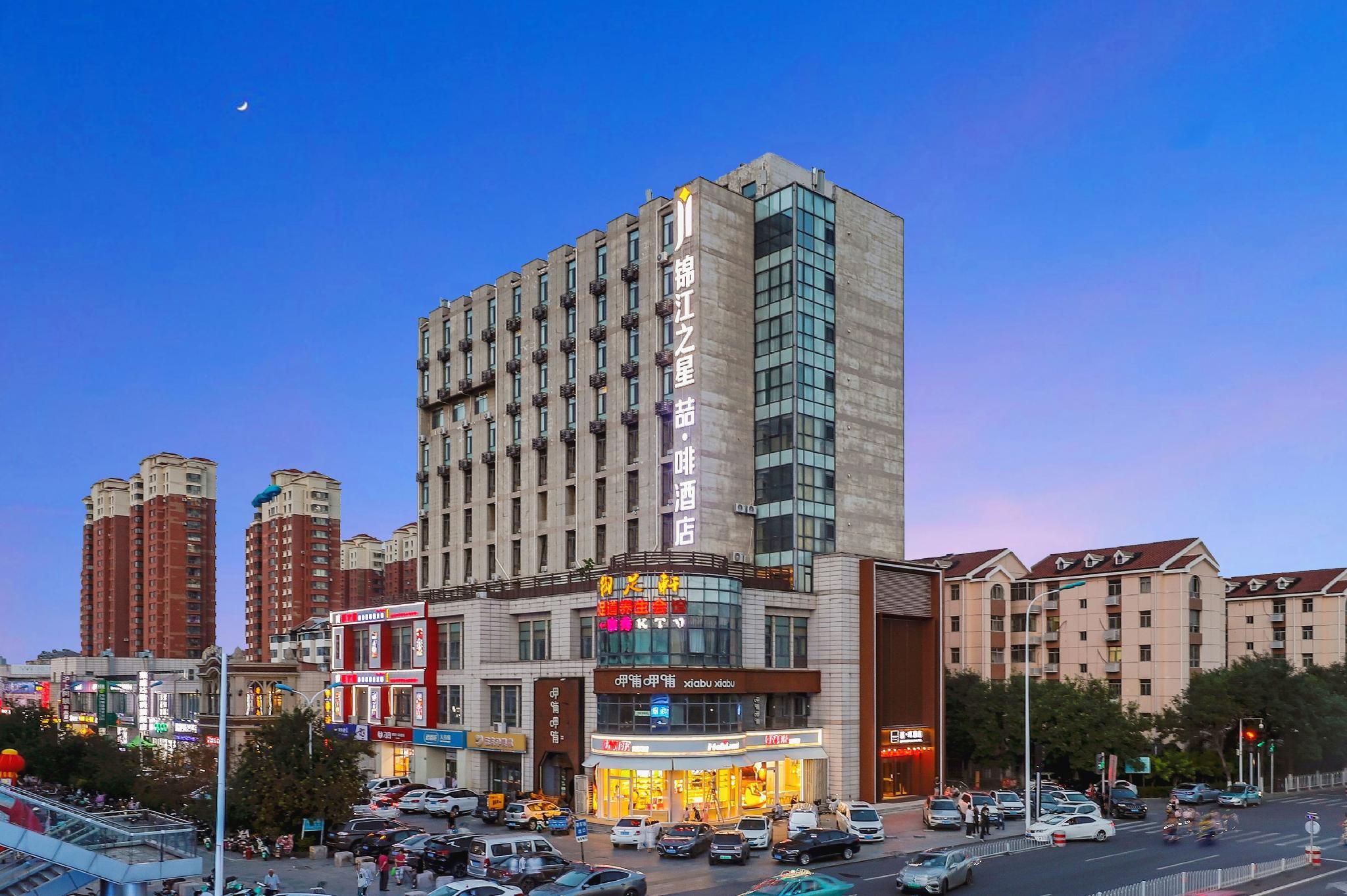 Un hotel de varios pisos con un letrero llamativo, rodeado de otros edificios y una calle concurrida.