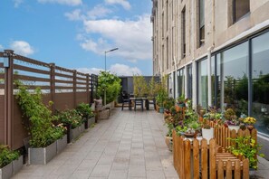 A rooftop terrace with a seating area, potted plants, and a view of a building. - Jinjiang Inn (Tianjin South Railway Station) (Tianjin)