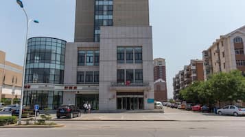 A multi-story building with a modern design, featuring a prominent glass facade and a sign for a hotel named 'Jinjiang Inn'.