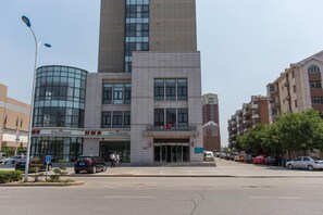 Ein mehrstöckiges Gebäude mit modernem Design, gekennzeichnet durch eine markante Glasfassade und ein Schild für ein Hotel namens 'Jinjiang Inn'.