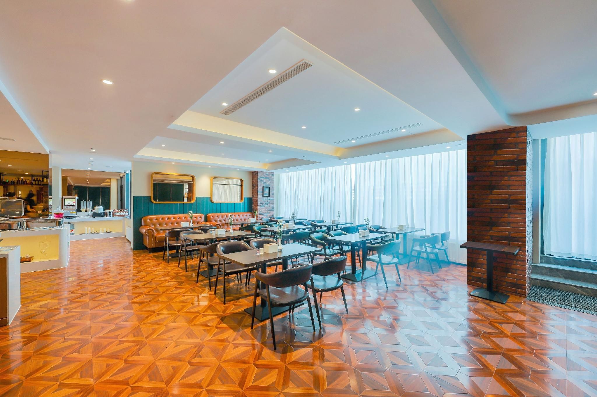 A spacious dining area with multiple tables and chairs, a bar area in the background, and a modern ceiling design.