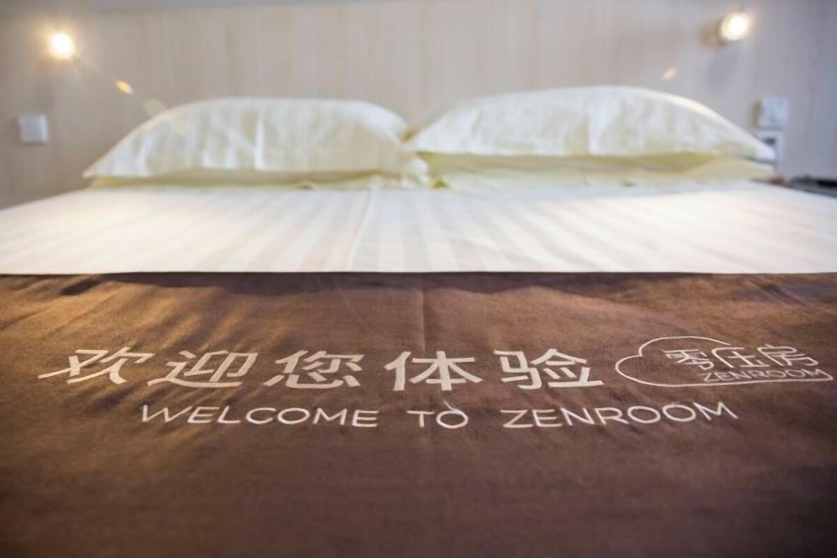 A bed with a blanket that reads 'WELCOME TO ZENROOM' in both English and Chinese.