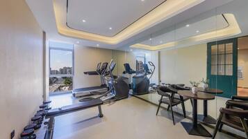 Un gimnasio moderno con máquinas de cardio, estaciones de pesas y vistas a la ciudad.