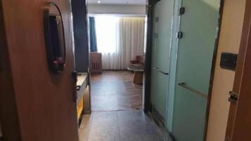A hotel hallway with a wooden door, a green wall, and a seating area with a table and chairs.