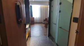 A hotel hallway with a wooden door, a green wall, and a seating area with a table and chairs.