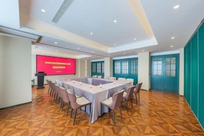 A conference room with a large table, chairs, a podium, and a screen.
