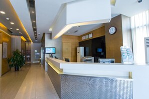 A hotel reception area with a modern design, including a reception desk, a clock, and a digital screen. - Jinjiang Inn (Tianjin South Railway Station) (Tianjin)