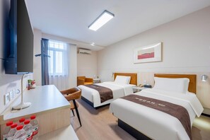 Habitación de hotel con dos camas, un escritorio, una silla, un televisor y una ventana con cortinas.