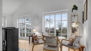 A spacious room with large windows, a dining area with wicker chairs, a small table, and a refrigerator. - Lovely home in ølsted with kitchen (Ølsted)