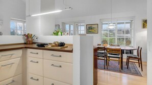 A modern kitchen with a central island, wooden cabinets, and a dining area with a table and chairs. - Lovely home in ølsted with kitchen (Ølsted)