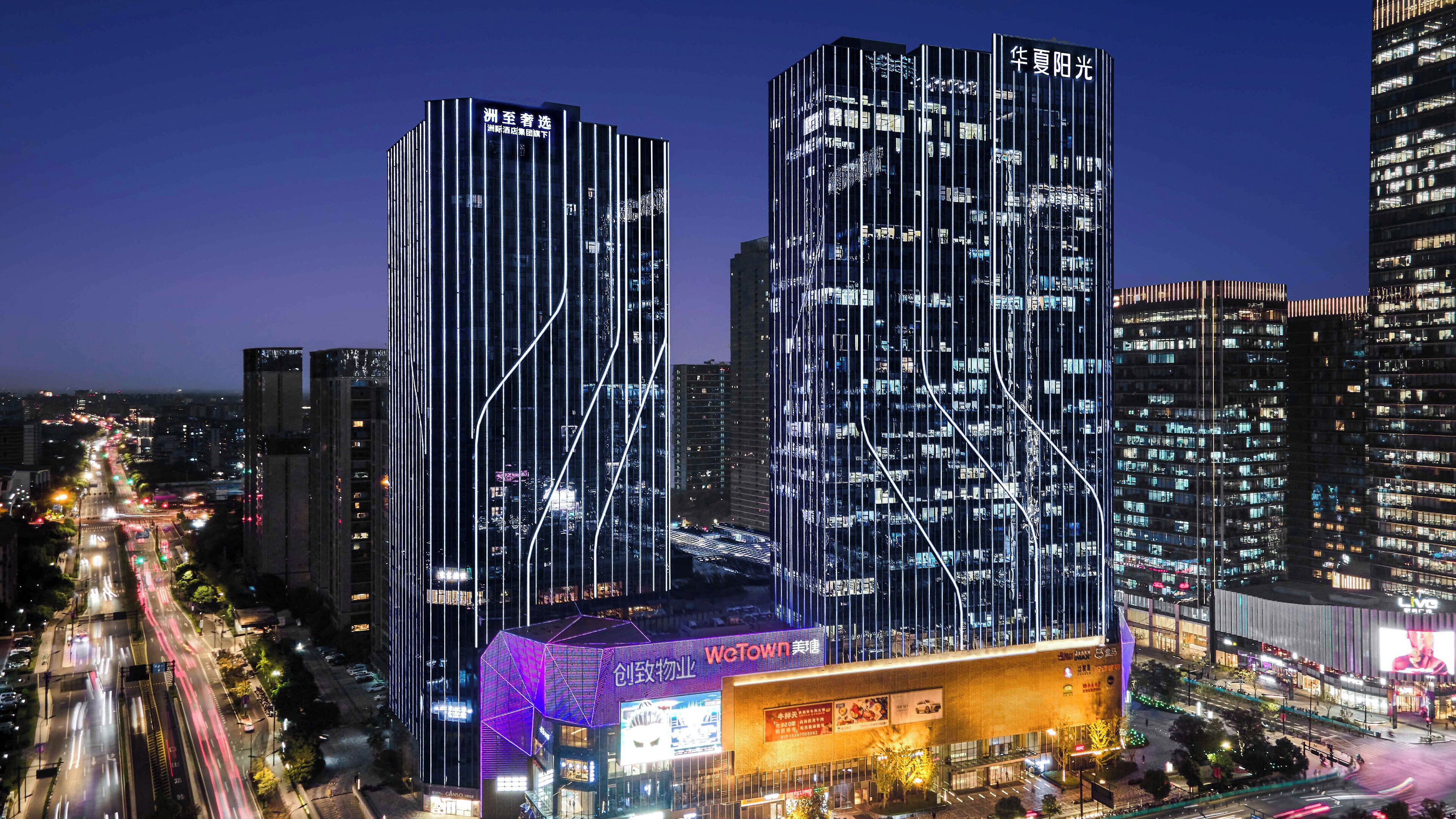 En modern skyskrapa med upplysta, vertikala linjer och en framträdande skylt med texten ”WeTown”.