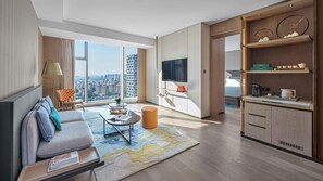 A modern living room with a sofa, coffee table, and a TV. There is a large window offering a city view. - Hangzhou Huaxia Center Hotel, Vignette Collection by IHG (Hangzhou)