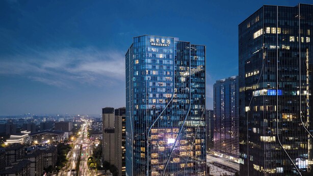 Un moderno edificio de gran altura con fachada de vidrio y ventanas iluminadas.