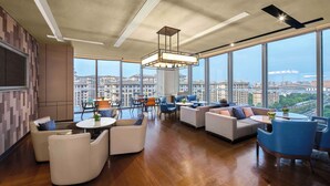 Un moderno espacio de relax con vistas a la ciudad, con sofás, mesas y un amplio ventanal.