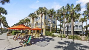 A hotel with outdoor seating and palm trees. - "Golden on 30A" | Gulf Views | Pool & hot tub | Tennis | Walk to Shops & Restaurants (Santa Rosa Beach)