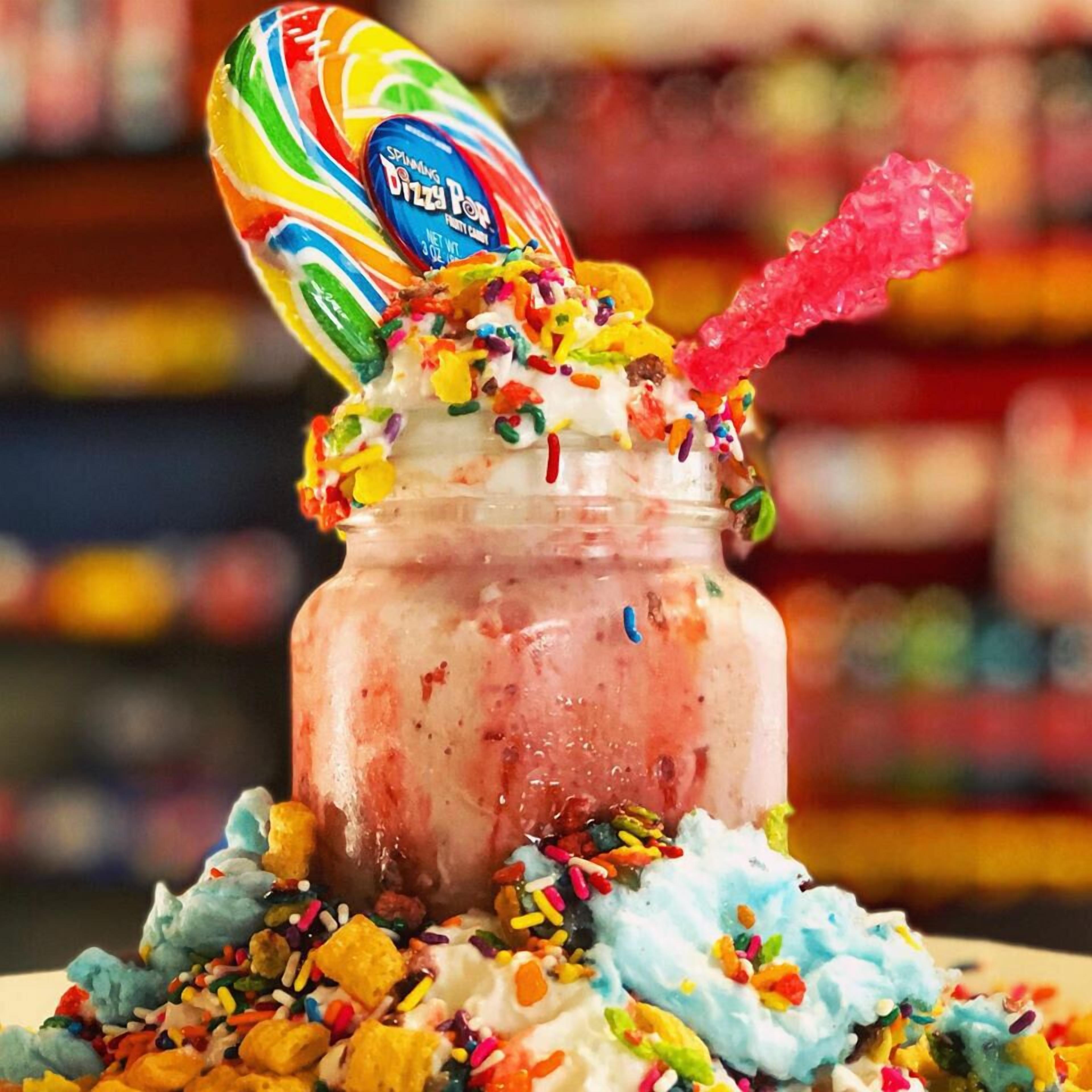 A colorful dessert with a lollipop and sprinkles.