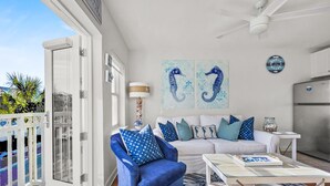 A modern living room with a blue armchair, white sofa, and patterned rug. - "Golden on 30A" | Gulf Views | Pool & hot tub | Tennis | Walk to Shops & Restaurants (Santa Rosa Beach)