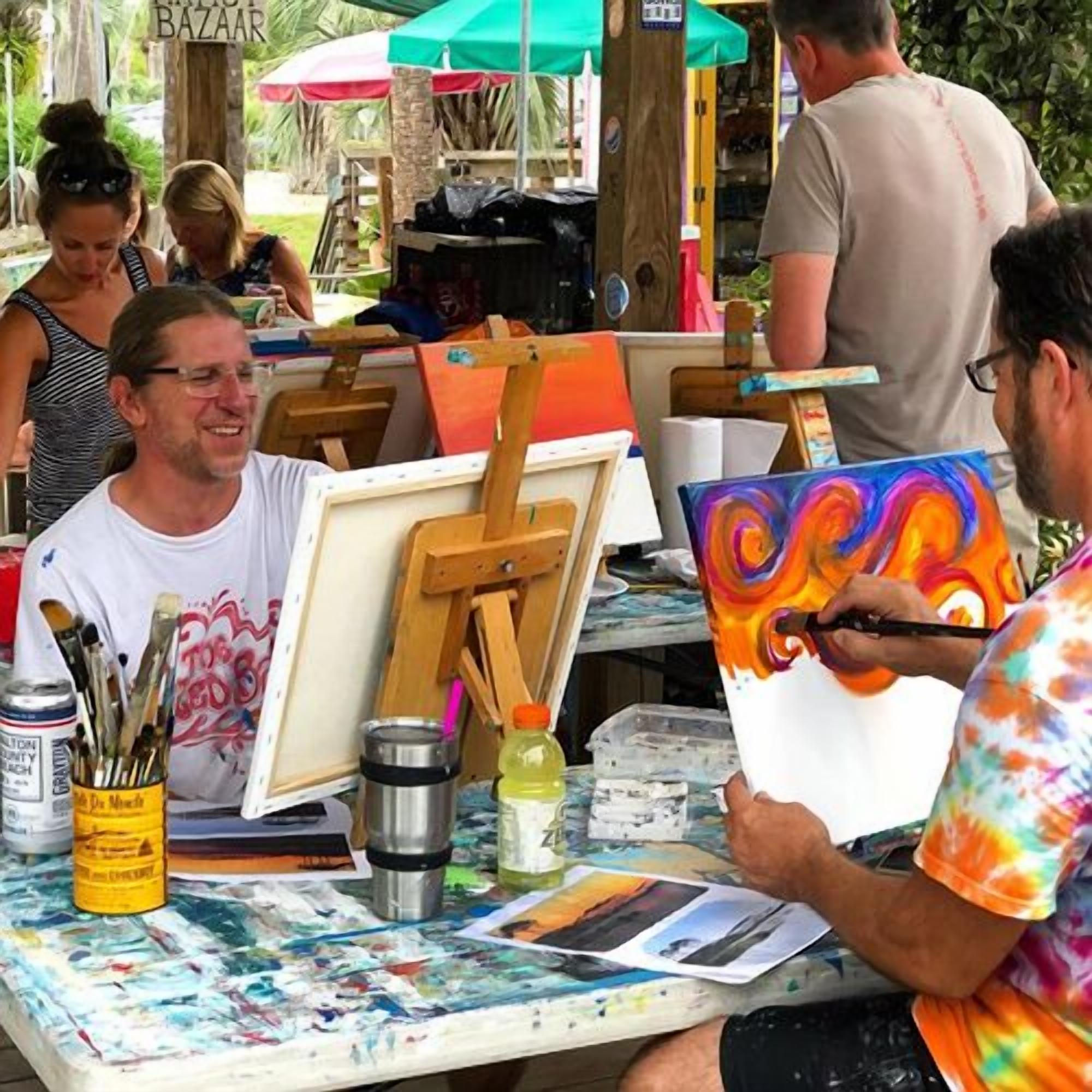 Un corso d'arte all'aperto con cavalletti, colori e tele.