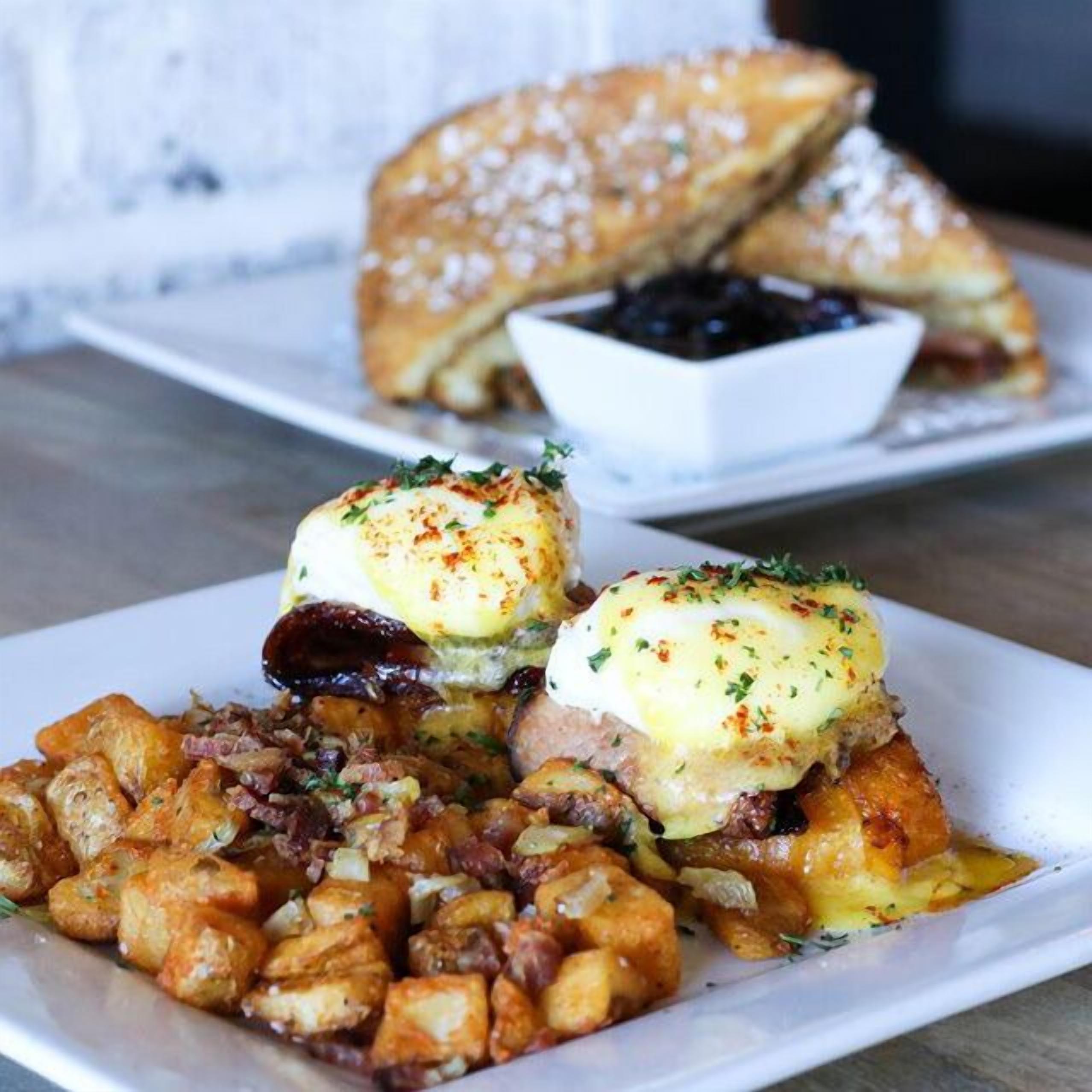 A plate of food with eggs benedict and hash browns.