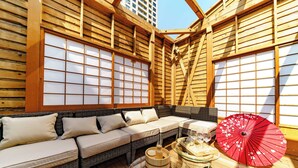 A traditional Japanese-style room with tatami flooring, a low wooden ceiling, and sliding shoji screens. There is a sofa set with cushions and a red floral umbrella on a table. - KONJAKUSO Osaka Shinsaibashi "TARUKAISEN" Rooftop SPA (Osaka)