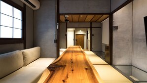 Un interior moderno con una larga mesa de madera, un sofá y vistas a un pasillo.