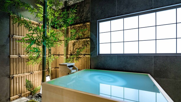 A modern spa with a large glass-enclosed hot tub, bamboo decor, and a view through a large window. - KONJAKUSO Osaka Bentencho "HIKARIYUYA" Projection Mapping SPA (Osaka)