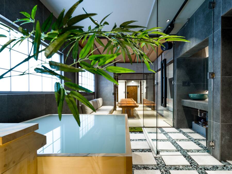 Un interior moderno con un ventanal grande, una mesa de madera y una planta de bambú.