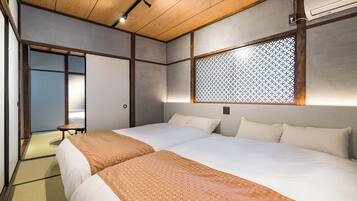 A hotel room with two beds, a wooden ceiling, a wall-mounted air conditioner, and a sliding door leading to a bathroom.