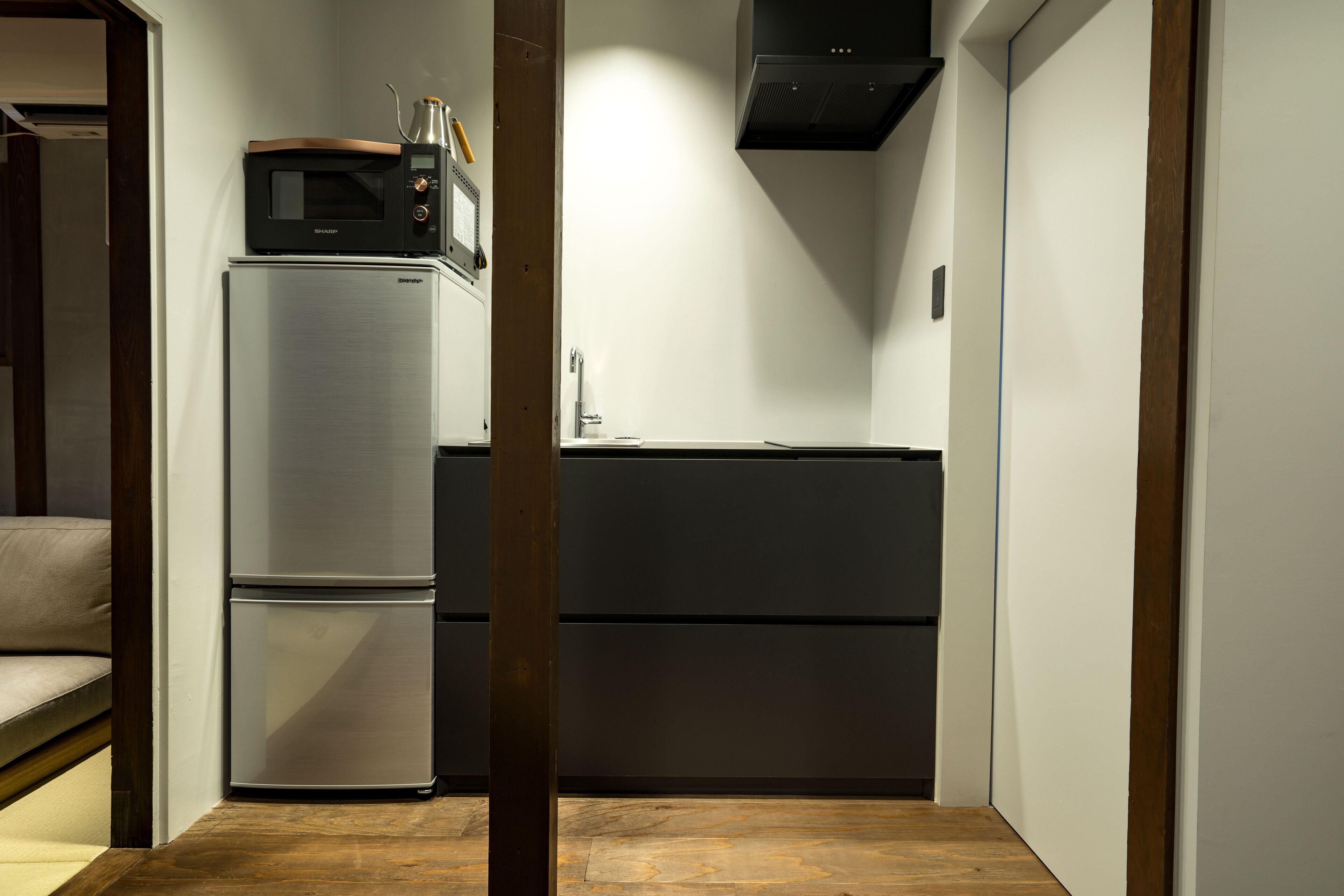 Una cocina compacta con un refrigerador de acero inoxidable, un microondas y un horno empotrado.