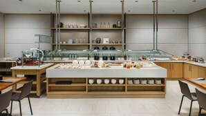 A modern kitchen with a central island, wooden cabinets, and a variety of kitchenware and appliances. - AC by Marriott Portland Beaverton (Beaverton)