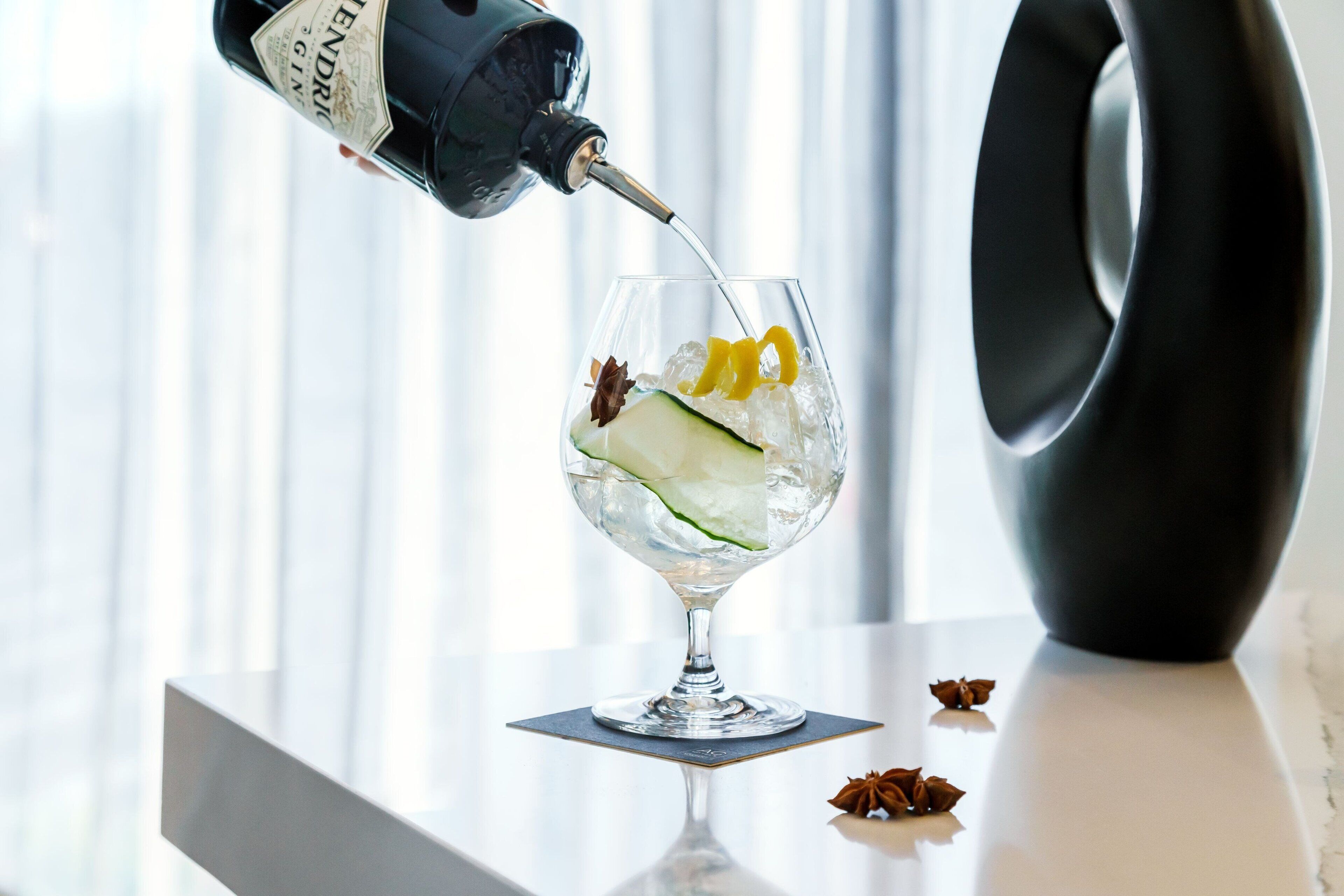 On verse un cocktail dans un verre rempli de glaçons et agrémenté de quelques décorations.