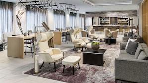 A modern hotel lobby with a seating area, a bar, and a bookshelf. - AC by Marriott Portland Beaverton (Beaverton)