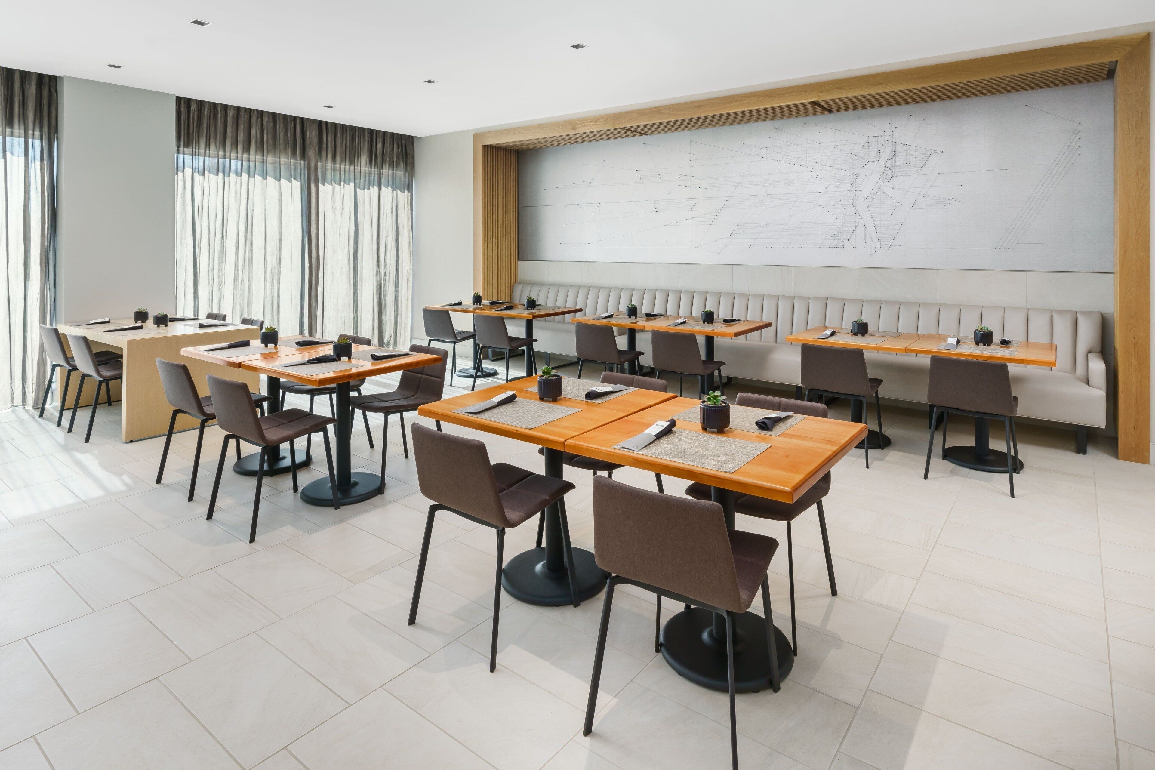A modern conference room with multiple tables and chairs, a large map on the wall, and a seating area with a bench.