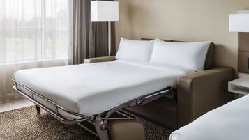 A hotel room with a bed, bedside tables, and a window with curtains.