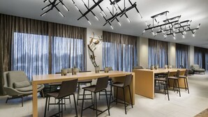 A modern conference room with a long table, multiple chairs, and a decorative wall piece. - AC by Marriott Portland Beaverton (Beaverton)