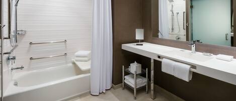 A modern bathroom with a bathtub, a vanity with a mirror, and a towel rack.