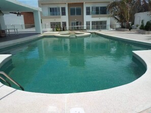 Una piscina al aire libre, sillones reclinables de piscina