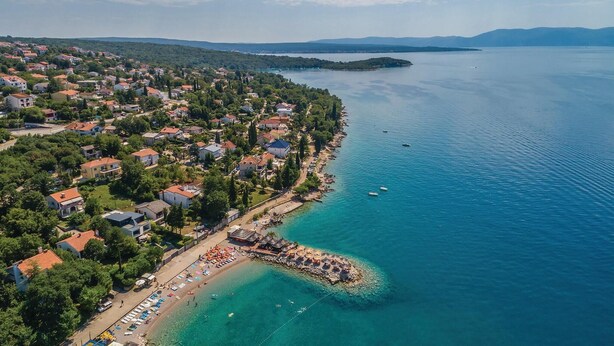 Luftaufnahme einer Küstenstadt mit Strand, Häusern und Booten.