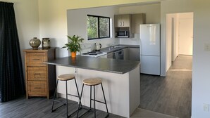 Una cocina moderna con una isla central, taburetes de bar, microondas y refrigerador.