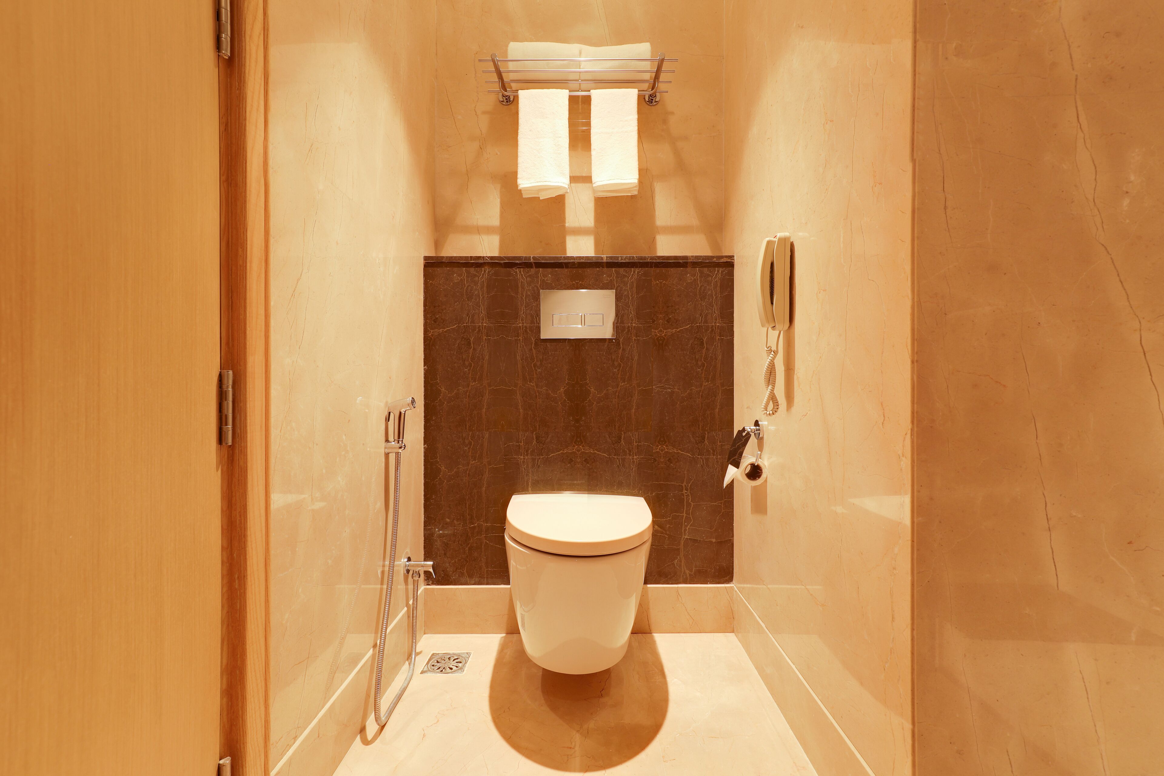 A compact bathroom with a toilet, a shower, and a towel rack.